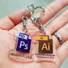 a person holding two different types of plastic key chains in their hand, with the words psd and asdadassiss printed on them