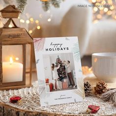 a christmas card sitting on top of a table next to a lantern and some candles