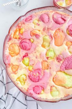 a pizza with different colored toppings sitting on top of a table next to a glass bowl