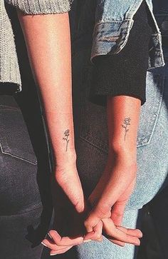 two people holding hands with small tattoos on them