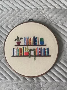 a cross stitch book shelf with books on it and a potted plant in the middle