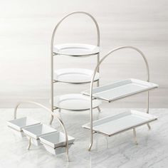 three tiered serving trays with white dishes on them and one holding two plates