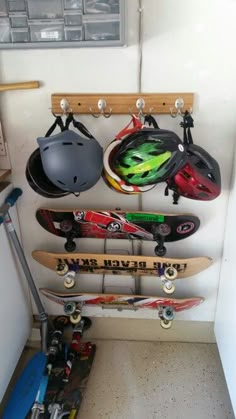 several skateboards and helmets are hanging on a rack in a room with white walls