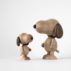 two wooden toy dogs standing next to each other on a white surface with one dog looking at the other