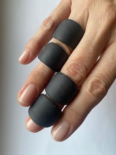 a woman's hand with two black rings on top of her fingers and one ring in the middle