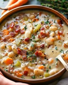 a person holding a bowl of soup with carrots and parsley on the side