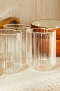 two clear glass cups sitting on top of a table next to a wooden spoon and bowl