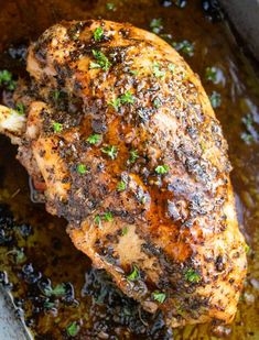 a close up of a piece of chicken in a pan with sauce and parsley