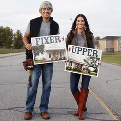 a man and woman holding up signs in the middle of a street with houses behind them