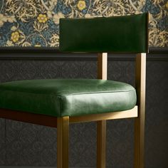 a green leather chair in front of a wallpapered wall with gold trimming