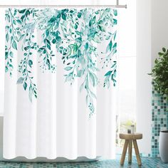 a shower curtain with green leaves on it in a bathroom next to a blue tiled floor