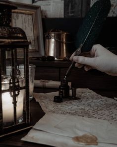 a person holding a feather quill and writing on a piece of paper with ink