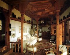 a living room filled with furniture and lots of woodwork on the ceiling above it