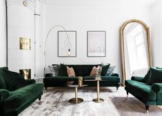 a living room filled with green couches and gold accents in front of a large mirror