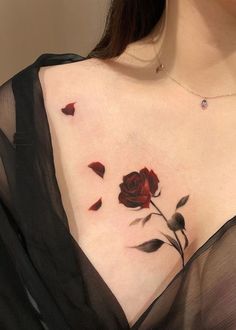 a woman's chest with a rose tattoo on her left side, and petals coming out of it