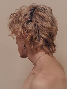 the back of a woman's head with blonde hair and earrings on her neck