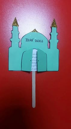 a piece of paper cut out to look like a mosque on a toothpick