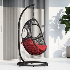 a hammock chair hanging on a stand next to a potted plant