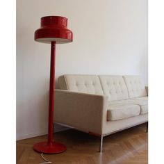 a red floor lamp sitting next to a white couch