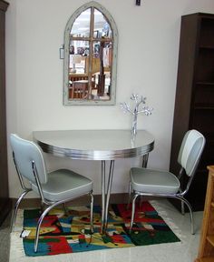 a dining room table with four chairs and a rug on the floor in front of it