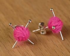 two pink balls of yarn sitting on top of each other in front of some metal pins