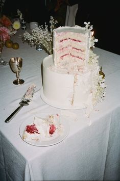 a large white cake sitting on top of a table next to a knife and fork