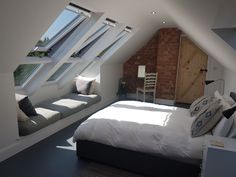 a bed sitting under two windows in a bedroom