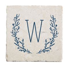 a stone coaster with the letter w on it and a laurel wreath design in blue ink