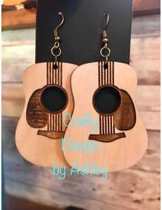 a pair of wooden guitar earrings hanging from hooks