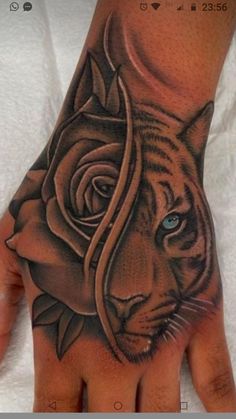 a hand with a tiger and rose tattoo on it