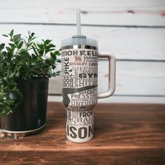 a coffee mug sitting on top of a wooden table next to a potted plant