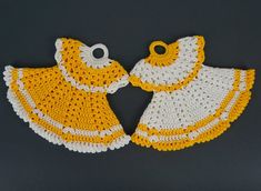 two yellow and white crocheted baby bibs on a gray surface with one being held by the other