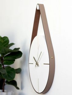 a clock is hanging on the wall next to a potted plant