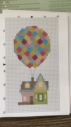 a cross stitch pattern with a hot air balloon in the shape of a house on it