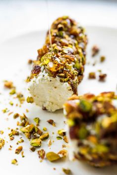 a white plate topped with two pieces of cake covered in nuts and pistachio