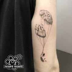 a person with a tattoo on their arm holding two heart shaped balloons in the shape of a brain