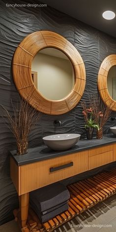 two round mirrors are on the wall in this bathroom with black countertops and wood accents