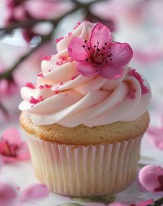 a cupcake with white frosting and pink flowers