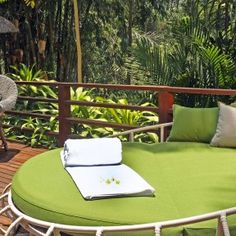 a green day bed on a wooden deck with an umbrella and table in the background