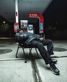 a man is sleeping on a chair in front of a gas station with his eyes closed