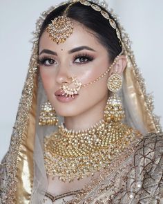 a woman in a bridal outfit with jewelry on her face and headpieces