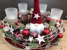 a christmas centerpiece with red and white decorations, candles and santa claus's hat