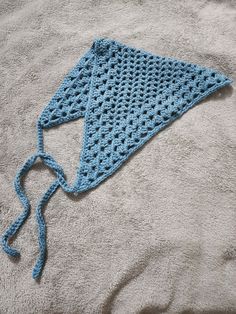 a blue crocheted triangle laying on top of a blanket