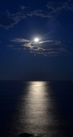 the moon is shining over the ocean at night