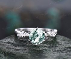 a green and white stone ring on top of a rock