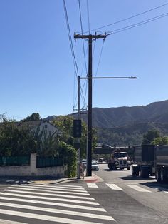 an intersection with cars and trucks on the road in front of some hills that are behind them