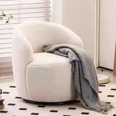 a white chair sitting on top of a black and white floor next to a window