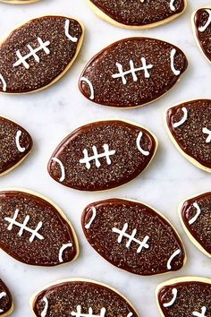 football cookies with chocolate frosting and white icing are arranged on a marble surface