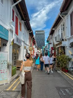 several people walking down the street in front of shops and buildings with red shutters