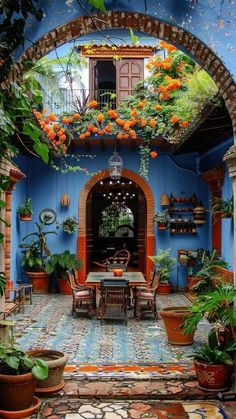 an outdoor dining area with potted plants and flowers on the ceiling, in front of a blue wall